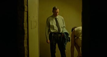 Movie still from “Great Freedom” (2021), directed by Sebastian Meise – A man in a dress shirt and tie holding a jacket; Medium shot, Over the shoulder angle