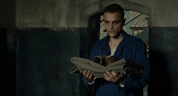 Movie still from “Great Freedom” (2021), directed by Sebastian Meise – A man holding a newspaper in his hands; Medium shot, High angle