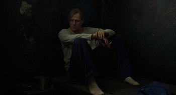 Movie still from “Great Freedom” (2021), directed by Sebastian Meise – A man sitting on the ground in a dark room; Medium shot, High angle