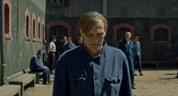 Movie still from “Great Freedom” (2021), directed by Sebastian Meise – A man standing in front of a group of people; Medium shot, Over the shoulder angle