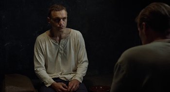 Movie still from “Great Freedom” (2021), directed by Sebastian Meise – A man sitting in front of another man in front of a black wall; Medium shot, Over the shoulder angle