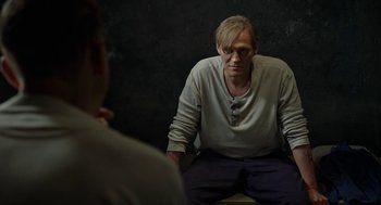 Movie still from “Great Freedom” (2021), directed by Sebastian Meise – A man sitting in front of another man in front of a black wall; Medium shot, Over the shoulder angle