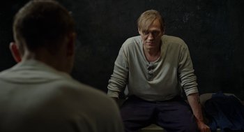 Movie still from “Great Freedom” (2021), directed by Sebastian Meise – A man sitting in front of another man in front of a black wall; Medium shot, Over the shoulder angle