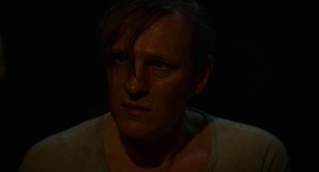 Movie still from “Great Freedom” (2021), directed by Sebastian Meise – A man with long dark hair is looking at the camera; Close Up shot, Over the shoulder angle