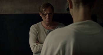 Movie still from “Great Freedom” (2021), directed by Sebastian Meise – A man standing in front of a mirror with his arms crossed; Close Up shot, Over the shoulder angle