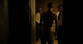 Movie still from “Great Freedom” (2021), directed by Sebastian Meise – A man standing next to two other men in a room; Medium shot, Over the shoulder angle