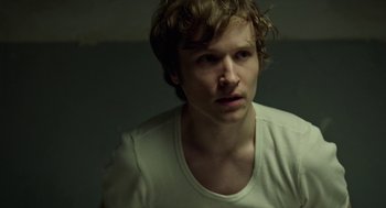 Movie still from “Great Freedom” (2021), directed by Sebastian Meise – A young man with blonde curly hair wearing a white t - shirt; Close Up shot, High angle
