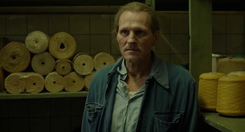 Movie still from “Great Freedom” (2021), directed by Sebastian Meise – A man in a blue shirt is standing in front of wood; Close Up shot, Low angle