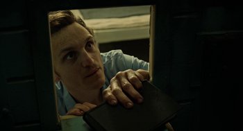 Movie still from “Great Freedom” (2021), directed by Sebastian Meise – A man leaning on a chair with his head on a book; Close Up shot, High angle