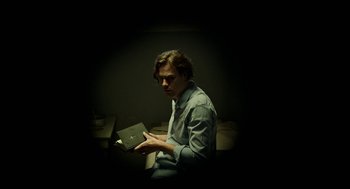 Movie still from “Great Freedom” (2021), directed by Sebastian Meise – A man holding a book in a dark room; Medium shot, Low angle