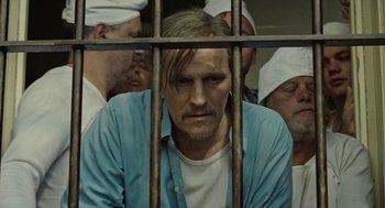 Movie still from “Great Freedom” (2021), directed by Sebastian Meise – A man in a jail cell with other inmates behind bars behind bars; Close Up shot, High angle