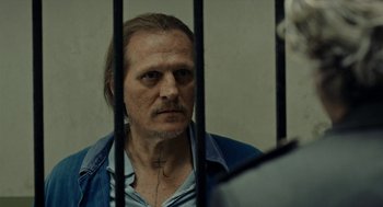 Movie still from “Great Freedom” (2021), directed by Sebastian Meise – A man in a blue shirt behind bars; Close Up shot, Over the shoulder angle