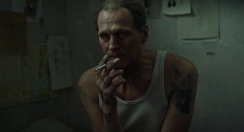 Movie still from “Great Freedom” (2021), directed by Sebastian Meise – A man smoking a cigarette while sitting in a bathroom; Close Up shot, High angle