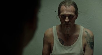Movie still from “Great Freedom” (2021), directed by Sebastian Meise – A man in a white tank top with tattoos on his arms; Close Up shot, Over the shoulder angle