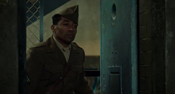 Movie still from “Great Freedom” (2021), directed by Sebastian Meise – A man in a military uniform standing next to a door; Medium shot, Over the shoulder angle