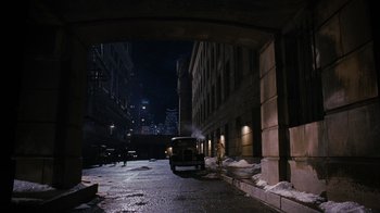 Movie still from “Grey Gardens” (2009), directed by Michael Sucsy – A car driving down a street next to a tall building at night; Extreme Wide shot, High angle