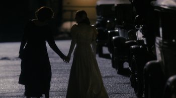 Movie still from “Grey Gardens” (2009), directed by Michael Sucsy – A woman and a man holding hands while walking down a street; Medium shot, Over the shoulder angle