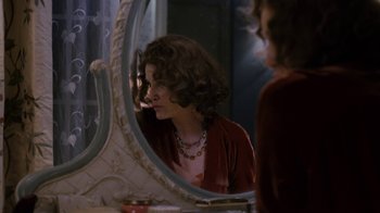 Movie still from “Grey Gardens” (2009), directed by Michael Sucsy – A woman looking in the mirror in front of a window; Medium shot, Over the shoulder angle
