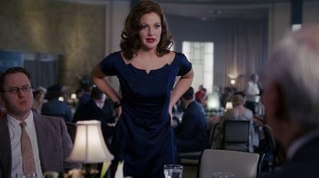 Movie still from “Grey Gardens” (2009), directed by Michael Sucsy – A woman in a blue dress standing in front of a table; Medium shot, Over the shoulder angle