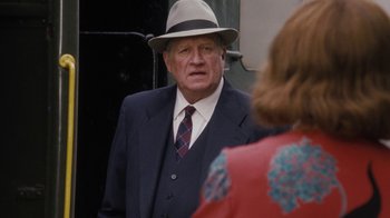 Movie still from “Grey Gardens” (2009), directed by Michael Sucsy – An older man wearing a suit and a hat; Medium shot, Over the shoulder angle