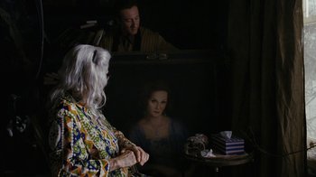 Movie still from “Grey Gardens” (2009), directed by Michael Sucsy – An older woman sitting in front of a painting of a woman; Medium shot, Over the shoulder angle