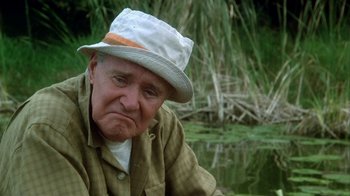 Movie still from “Grumpier Old Men” (1995), directed by Howard Deutch – An older man wearing a white hat sitting in front of a body of water; Close Up shot, Low angle