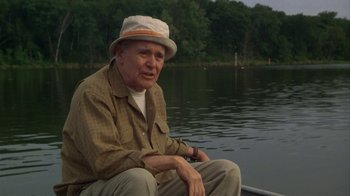 Movie still from “Grumpier Old Men” (1995), directed by Howard Deutch – An older man sitting on the back of a boat in the water; Medium shot, Low angle