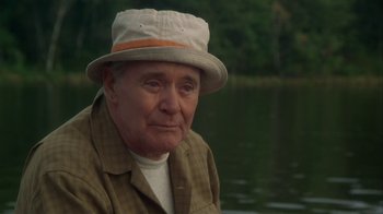 Movie still from “Grumpier Old Men” (1995), directed by Howard Deutch – An older man wearing a hat sitting in front of a body of water; Close Up shot, Low angle
