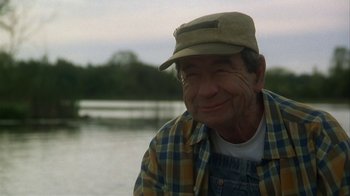 Movie still from “Grumpier Old Men” (1995), directed by Howard Deutch – An older man wearing a hat sitting in front of a body of water; Close Up shot, Low angle