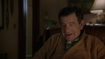 Movie still from “Grumpier Old Men” (1995), directed by Howard Deutch – An older man sitting in a chair smiling at the camera; Close Up shot, High angle