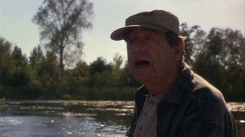 Movie still from “Grumpier Old Men” (1995), directed by Howard Deutch – An older man is standing in front of a body of water; Medium shot, Over the shoulder angle