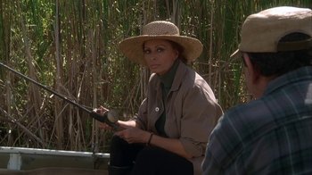 Movie still from “Grumpier Old Men” (1995), directed by Howard Deutch – A woman sitting on the ground holding a fishing pole; Medium shot, Over the shoulder angle