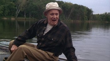 Movie still from “Grumpier Old Men” (1995), directed by Howard Deutch – An older man sitting on the back of a boat in the water; Medium shot, Low angle