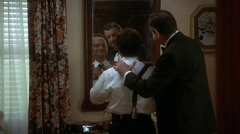 Movie still from “Grumpier Old Men” (1995), directed by Howard Deutch – A man in a suit fixing a man in a suit in front of a mirror; Medium shot, Over the shoulder angle