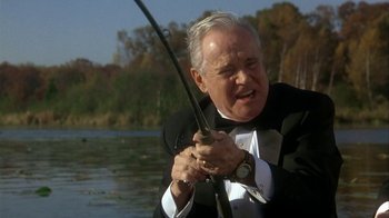 Movie still from “Grumpier Old Men” (1995), directed by Howard Deutch – An older man holding a fishing rod while standing on a boat; Medium shot, Low angle