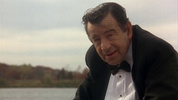 Movie still from “Grumpier Old Men” (1995), directed by Howard Deutch – An older man wearing a tuxedo sitting in front of a body of water; Close Up shot, Over the shoulder angle