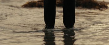Movie still from “Gully” (2019), directed by Nabil Elderkin – A person standing in the water with their feet in the water; Wide shot, Low angle