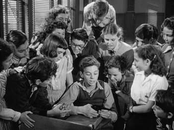 Movie still from “Gun Crazy” (1950), directed by Joseph H. Lewis – A group of young people gathered around a man; Medium shot, High angle