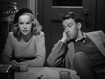 Movie still from “Gun Crazy” (1950), directed by Joseph H. Lewis – A man and a woman sitting next to each other at a table; Medium shot, Over the shoulder angle