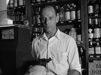 Movie still from “Gun Crazy” (1950), directed by Joseph H. Lewis – A black and white photo of a man holding a gun; Medium shot, Low angle