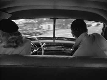 Movie still from “Gun Crazy” (1950), directed by Joseph H. Lewis – A man and a woman driving a car in the back of a car; Medium shot, Over the shoulder angle