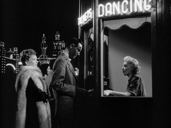 Movie still from “Gun Crazy” (1950), directed by Joseph H. Lewis – A man and a woman standing next to each other in front of a building; Wide shot, Low angle