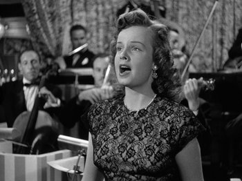 Movie still from “Gun Crazy” (1950), directed by Joseph H. Lewis – A woman singing in front of a group of people; Medium shot, Low angle