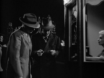 Movie still from “Gun Crazy” (1950), directed by Joseph H. Lewis – A couple of men standing next to each other on a street; Medium shot, Low angle