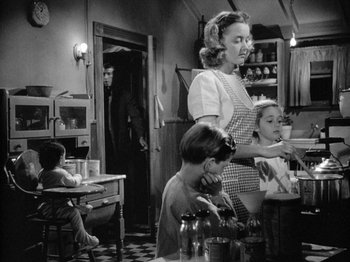 Movie still from “Gun Crazy” (1950), directed by Joseph H. Lewis – An old photo of a woman and children in a kitchen; Medium shot, Over the shoulder angle