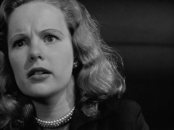 Movie still from “Gun Crazy” (1950), directed by Joseph H. Lewis – A black and white photo of a woman with a pearl necklace; Close Up shot, Low angle