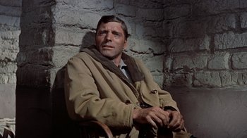 Movie still from “Gunfight at the O.K. Corral” (1957), directed by John Sturges – A man sitting in a chair wearing a coat; Close Up shot, Low angle