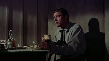 Movie still from “Gunfight at the O.K. Corral” (1957), directed by John Sturges – A man sitting at a table with a sandwich in his hand; Medium shot, Low angle