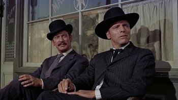 Movie still from “Gunfight at the O.K. Corral” (1957), directed by John Sturges – A couple of men sitting next to each other wearing hats; Medium shot, Low angle