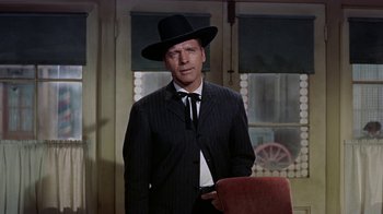 Movie still from “Gunfight at the O.K. Corral” (1957), directed by John Sturges – A man wearing a suit and a black hat; Medium shot, Low angle